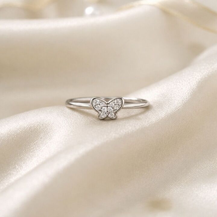 Silver butterfly ring on a soft beige fabric background