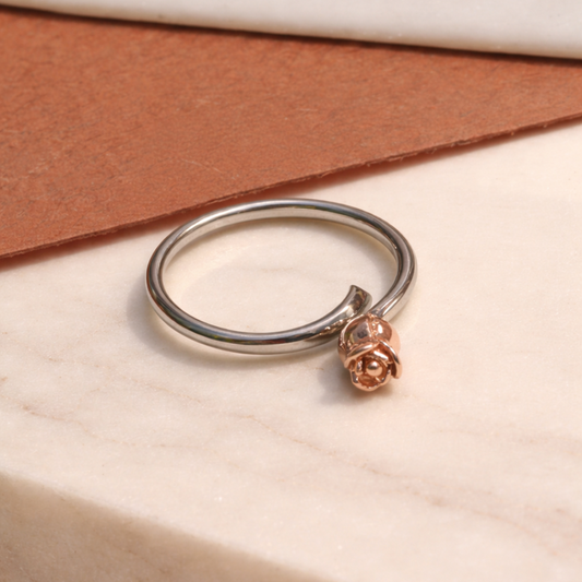 Silver ring with a rose-shaped charm on a beige surface