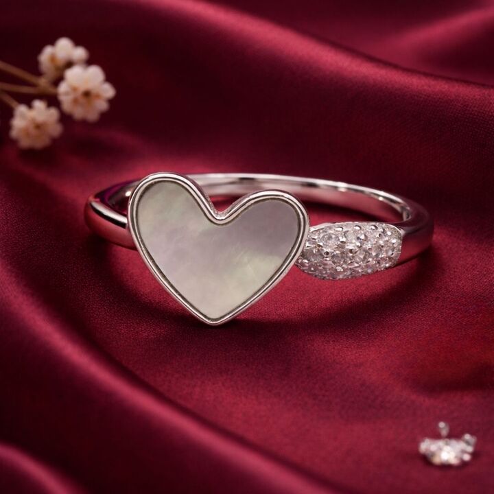 Heart-shaped ring with a textured band on a red fabric background