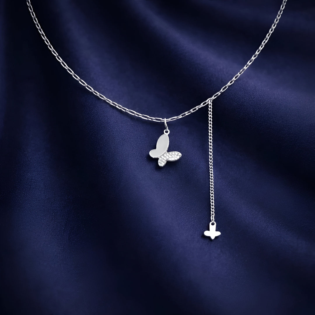 Silver butterfly necklace on a dark blue fabric background