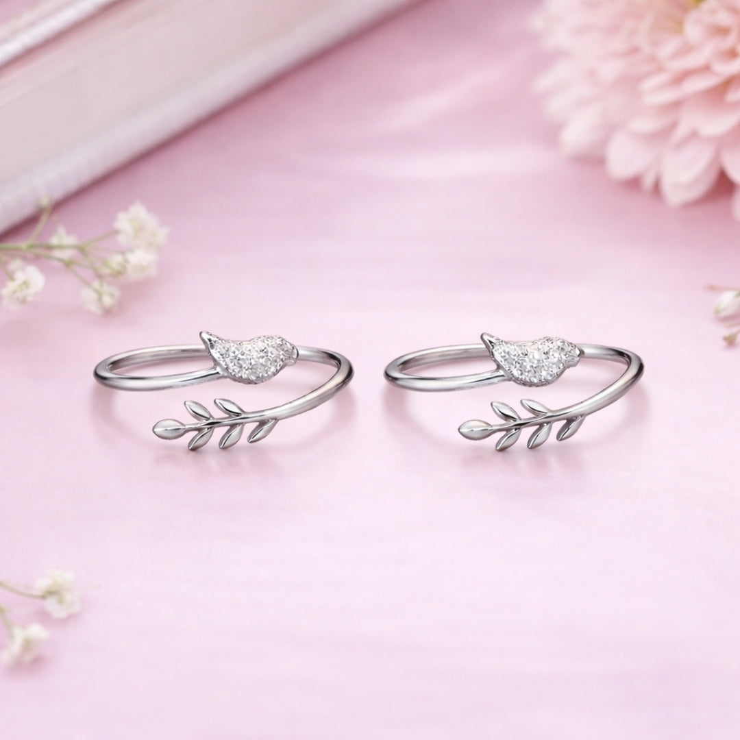 Silver rings with leaf designs on a pink background