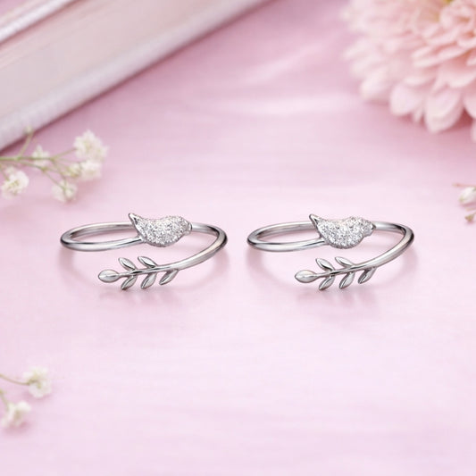 Silver rings with leaf designs on a pink background