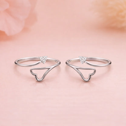 Silver heart-shaped rings on a soft pink background