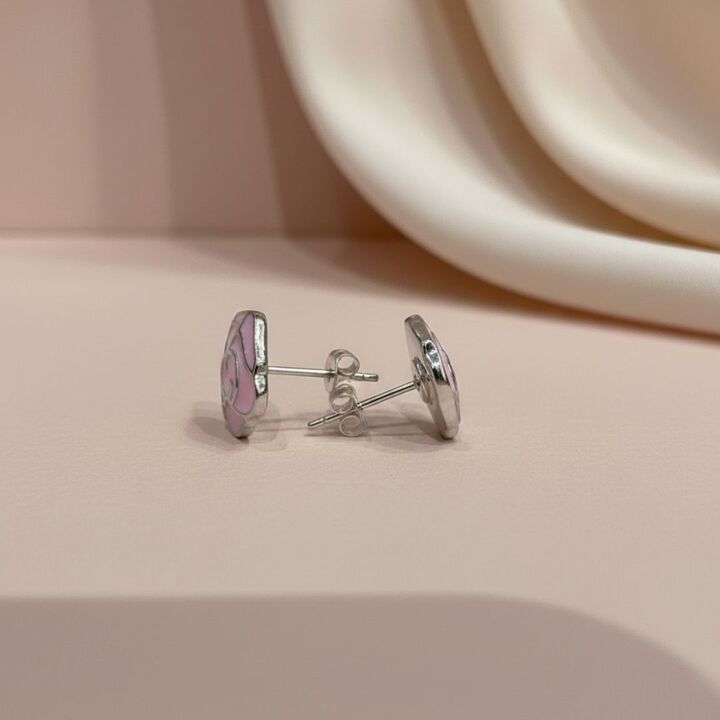 Silver earrings with pink floral design on a beige surface