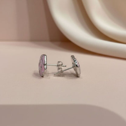 Silver earrings with pink floral design on a beige surface