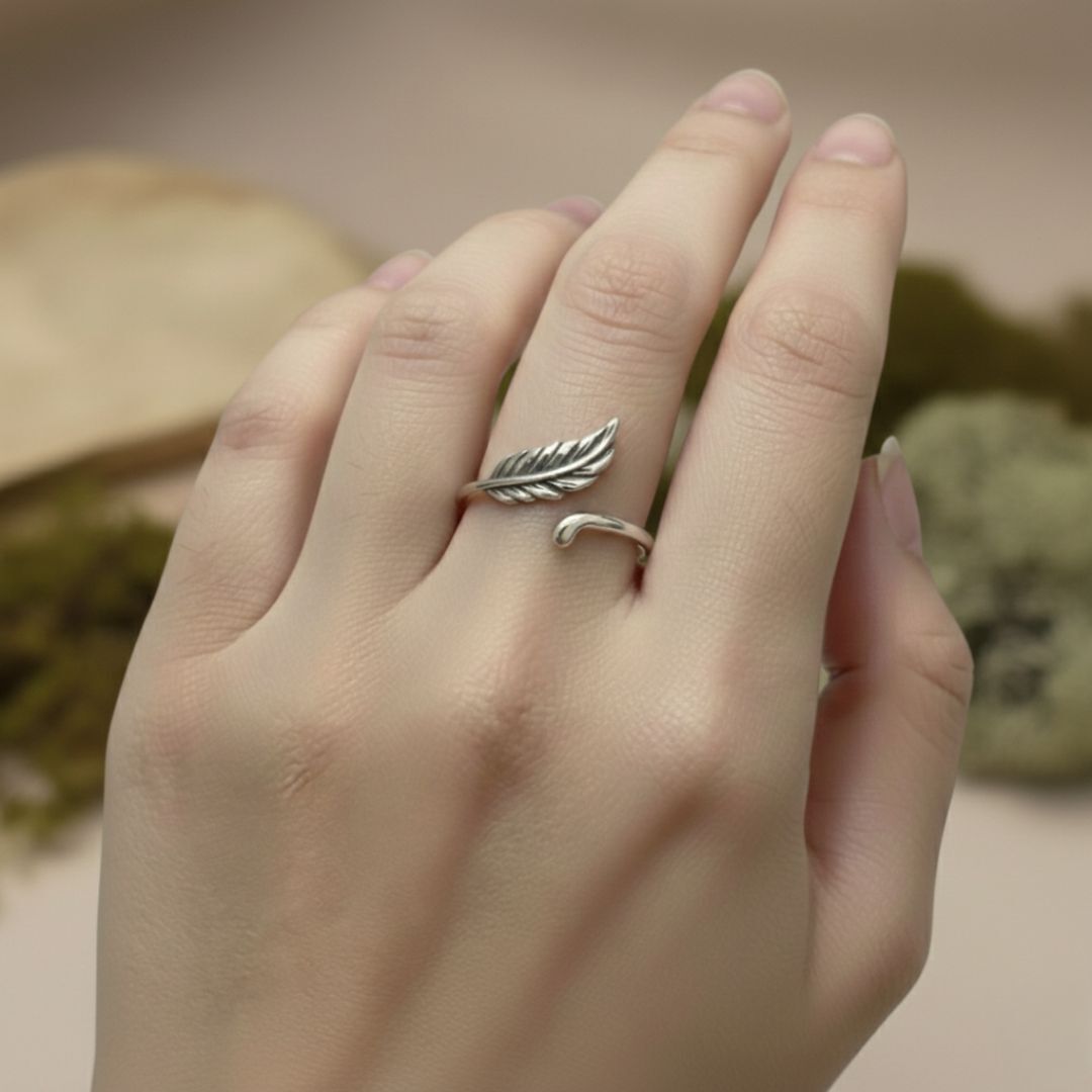 Silver leaf-shaped ring on a finger with a natural background