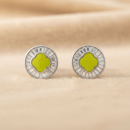 Round earrings with green center and silver border on beige background
