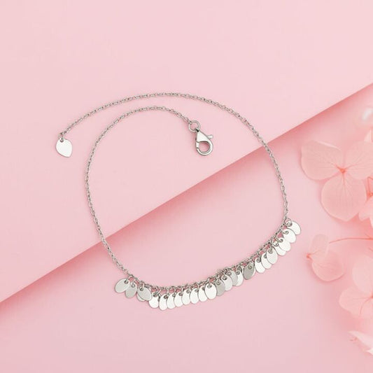 Silver necklace with circular pendants on a pink background