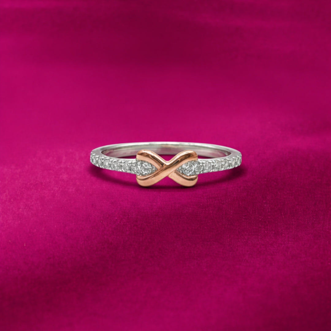 Two-finger ring with infinity symbol design on a pink background