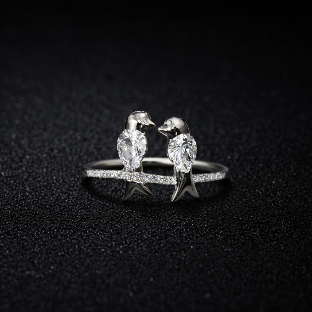 Silver ring with penguin designs on a dark textured background