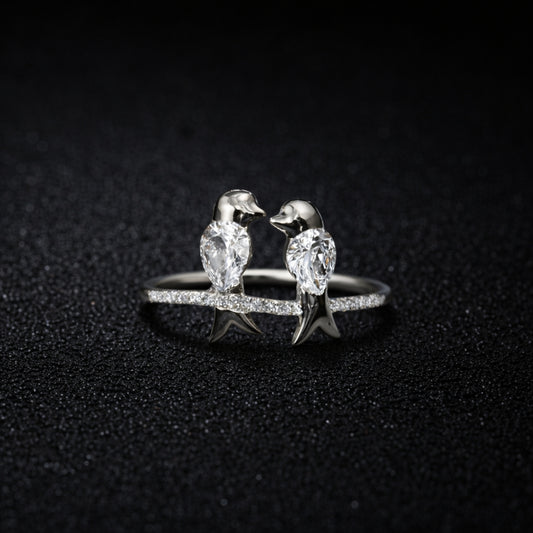 Silver ring with penguin designs on a dark textured background