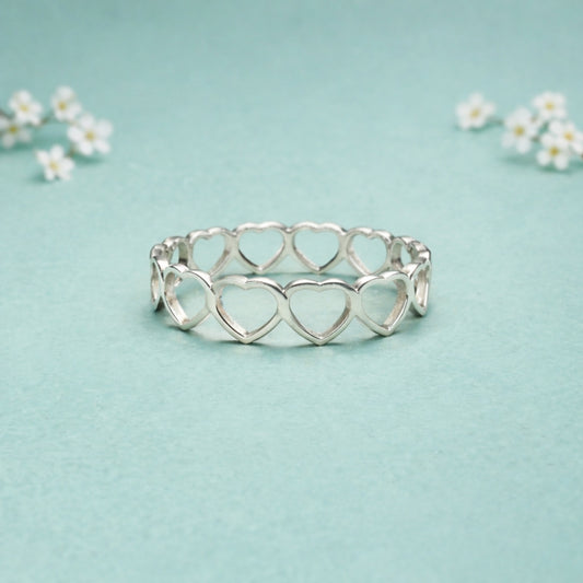 Silver ring with heart design on a light blue background