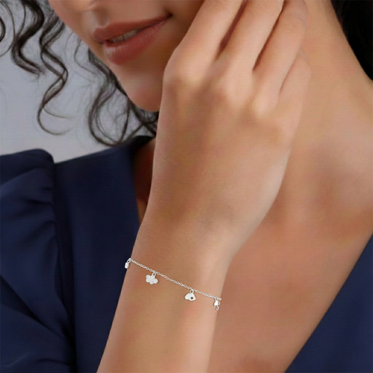 Close-up of a woman's wrist wearing a silver bracelet with heart charms against a neutral background